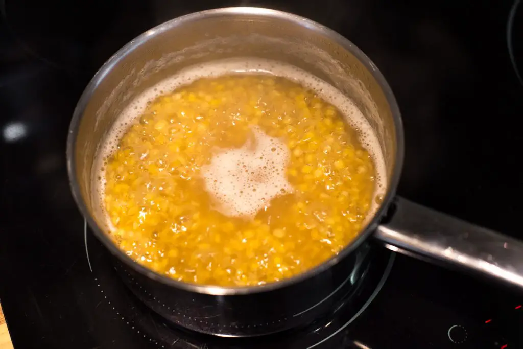Red lentils cooking in a pan of boiling water.
